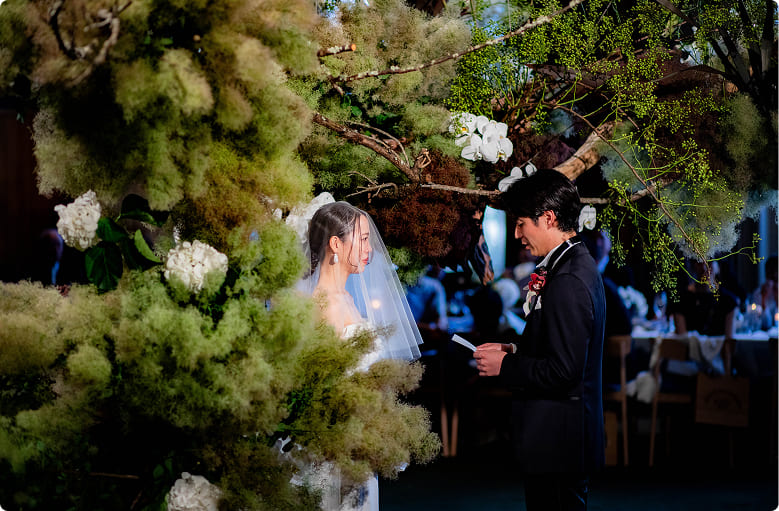 緑に囲まれたセレモニー中の新郎新婦｜誓いの言葉を読む感動的な瞬間