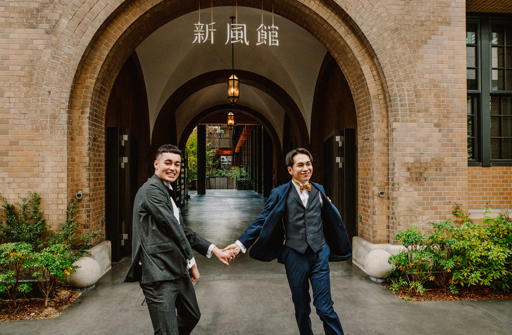 新風館のレンガアーチの下で手を繋いで歩く二人の新郎|エースホテル京都LGBTQ+ウェディング